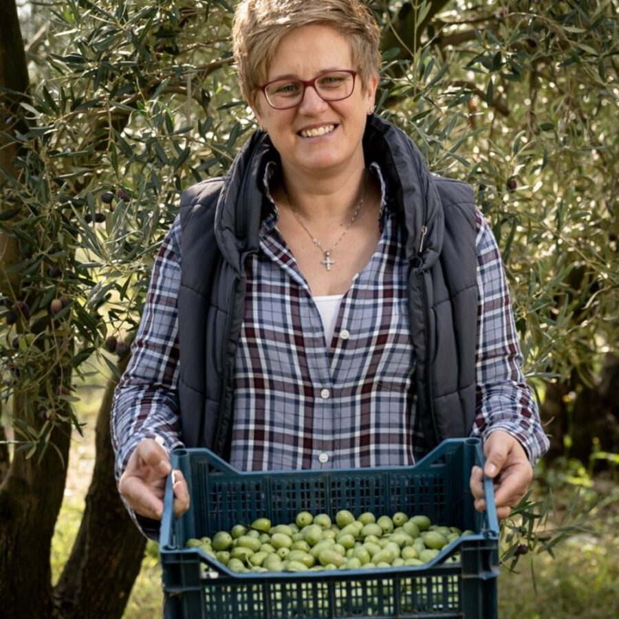 Julia Lakirdakis-Stefanou im Olivenhain mit einer Kiste frisch geernteten, grünen Oliven
